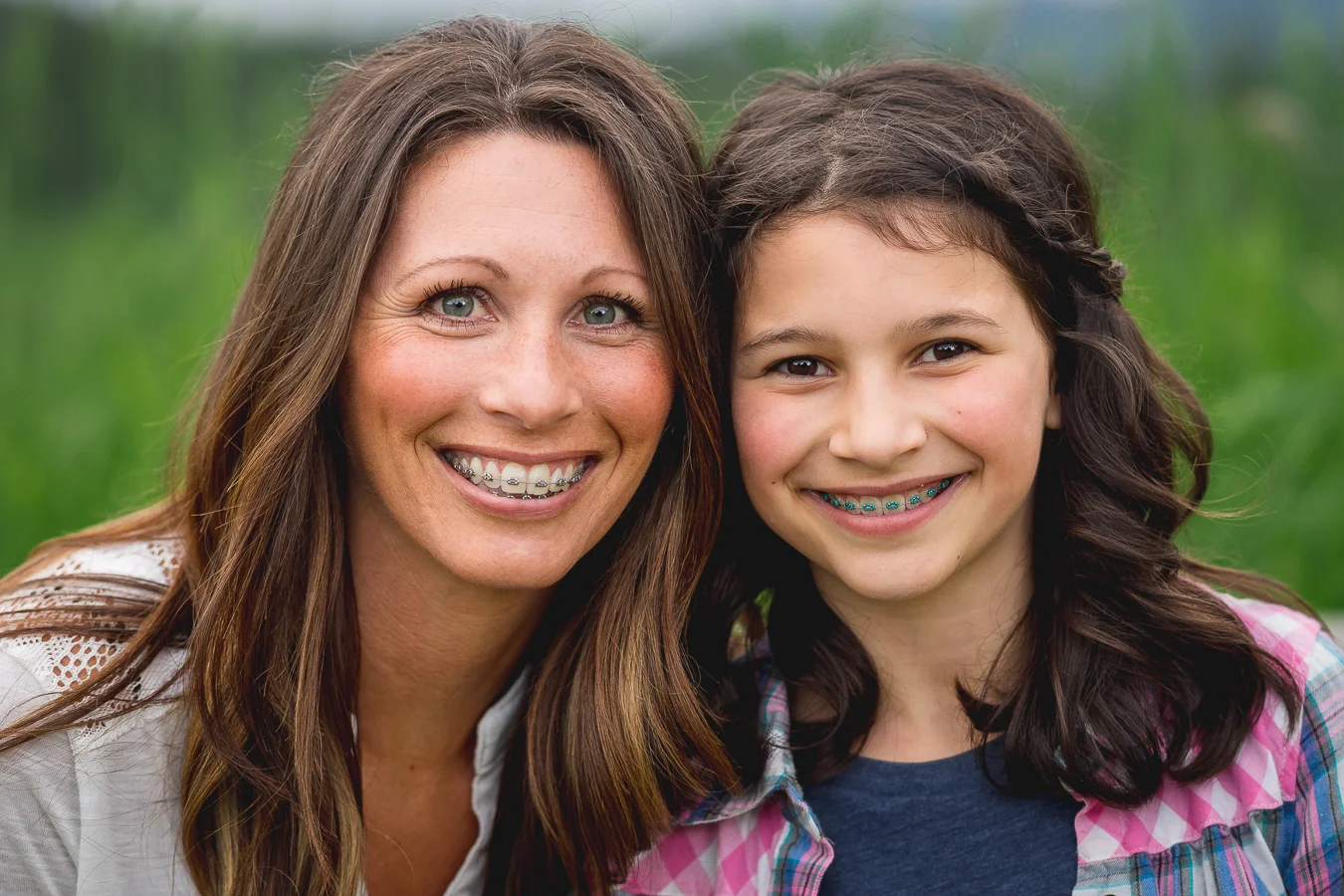 Smiling mother and daughter both wearing braces outdoors