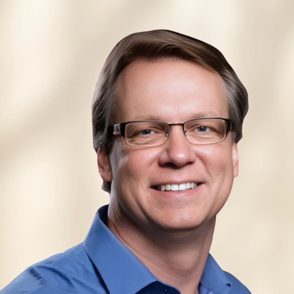 Smiling man with glasses and blue button-down shirt, professional headshot